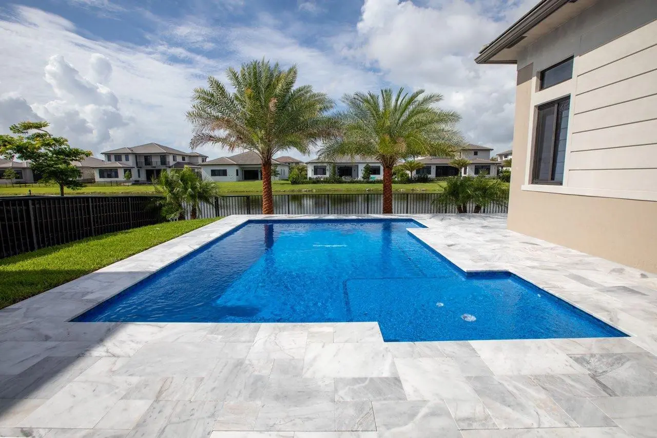 A modern swimming pool with marble pavers installed by professional contractors.
